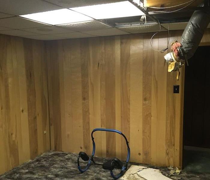 Basement with damaged ceiling and wood paneling
